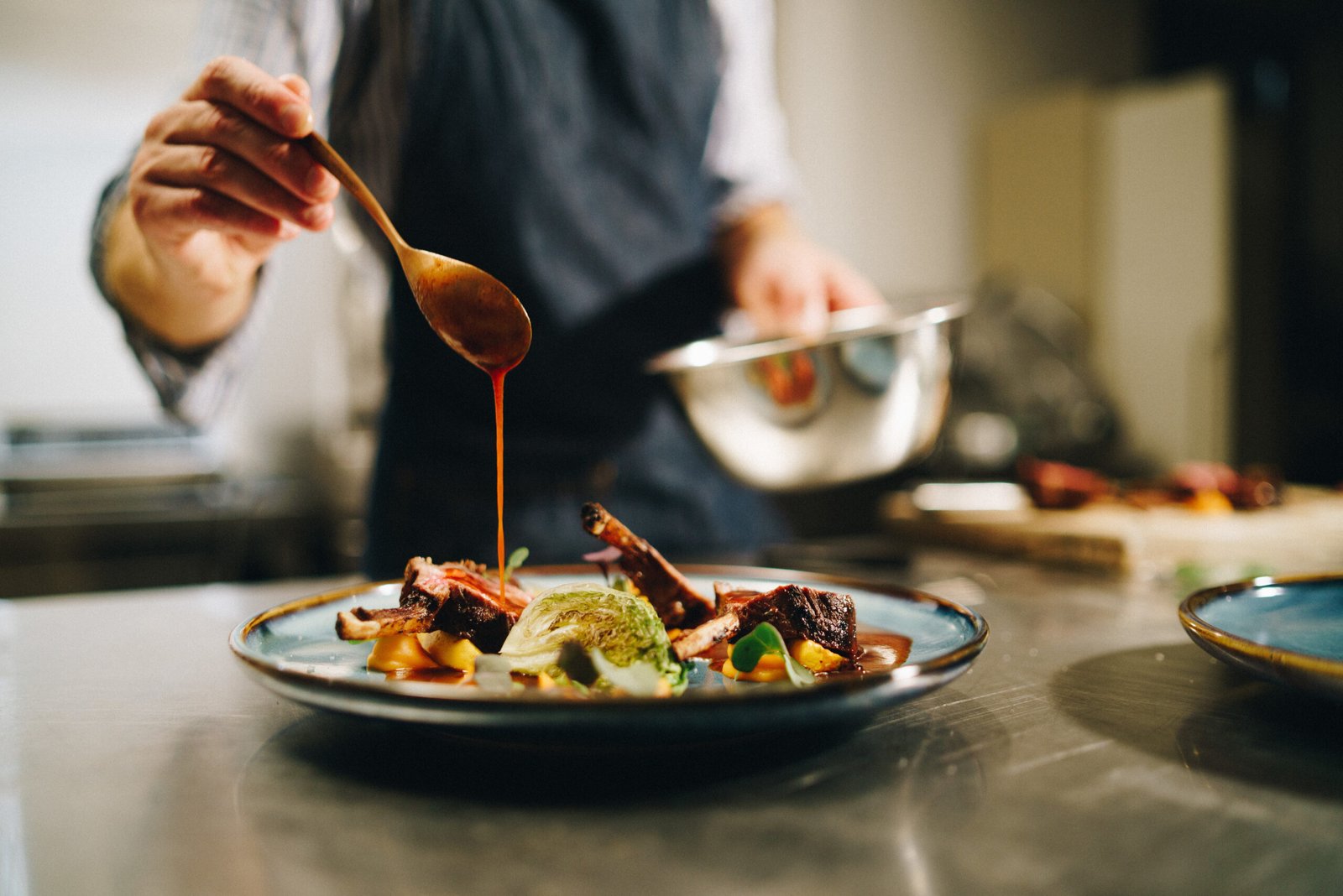 Chef pouring special sauce on pork ribs in the kitchen